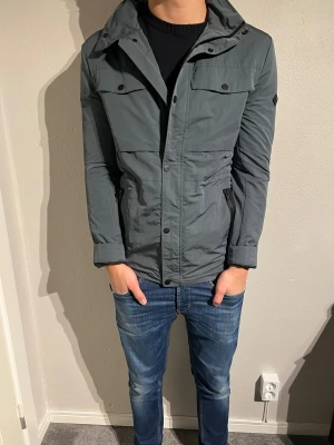 J Lindeberg jacka - Hej, säljer nu denna sjukt goa j.linderberg jackan i storlek M  som är grym nu till våren/ vintern, färgen på jackan är grön/grå men i ljuset ser den gråare ut, skicket är 8/10! Hör av er vid frågor