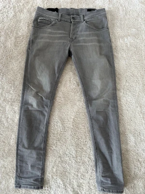 Grå skinny jeans från Dondup - Snygga grå jeans från Dondup, modell George Skinny Fit. De har klassisk femficksdesign, smal passform och coola detaljer som ljusgrå CC-logga på baksidan. Jeansen är tillverkade i mjukt denimtyg och har en modern, stilren look som passar till sneakers eller boots.