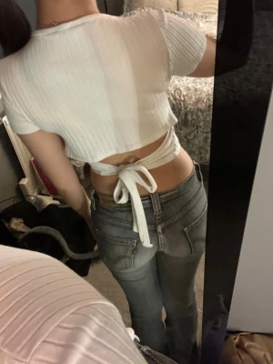 Vit ribbad tröja  - Den har band så man kan knyta en roset bak till. Den är liten i storleken så skulle säga den passar xs eller xxs.