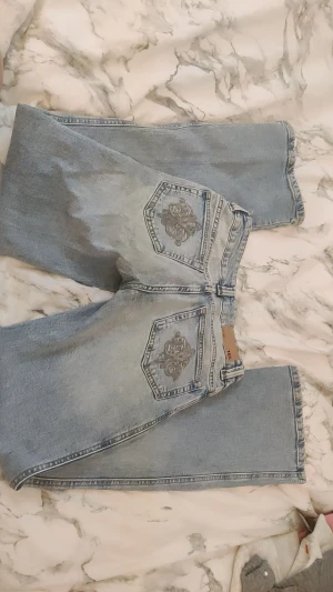 Ljusblåa låg midjade bootcut jeans från 157 - Ljusblå jeans med bootcut passform från lager 157. Snygga broderade detaljer på bakfickorna, byxorna är låg midjade och är i storlek S. Lite slitage nertill men de är inget man märker