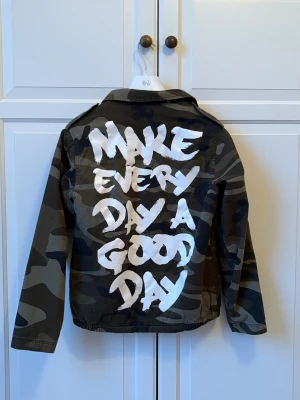 Camouflage overshirt - Riktigt snygg overshirt i camouflage från märket Atmosphere. Overshirten har fränt tryck på ryggen med texten 'MAKE EVERY DAY A GOOD DAY' i vitt. Den har klassisk krage, sidofickor och är fodradd men fleecematerial på insidan. Tveka inte på att skriva till mig på DM om mått mm😁
