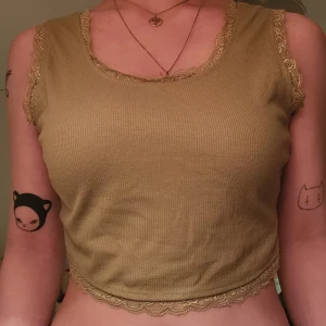 Grön croppad topp med spets - Grön croppad ribbad topp med spetsdetaljer vid halsringning, ärmkanter och nederkant.