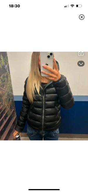  Colmar jacka  - Säljer en , glansig dunjacka från Colmar med huva och dragkedja framtill. Jackan har ett quiltat mönster, två sidofickor med dragkedja och en rund logotyp på vänster ärm. Perfekt för kalla dagar och har en snygg, modern look.