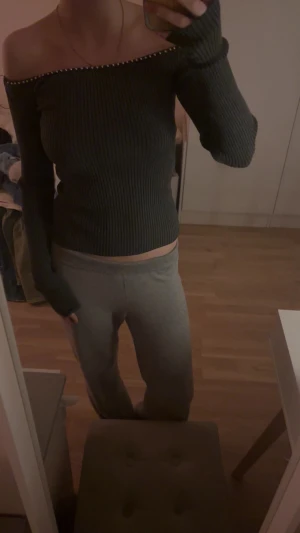 Grå ribbad offshoulder topp - Säljer en grå ribbad offshoulder topp med långa ärmar. Toppen har en snygg detalj med små pärlor längs den bara axeln. 