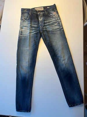 Replay Blue Jeans herrjeans blå - Snygga blå Replay Blue Jeans med slitningar och ljusa tvättade partier. Klassisk femficksmodell. Modell GEEBO. Fint använt skick. Inget att anmärka på.  29/32