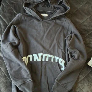 Svart hoodie från Dondup - Svart hoodie från Dondup med stor huva och tryckt logga över magen. Tröjan har klassisk känguruficka och ribbade muddar vid ärmslut och nederkant. Tillverkad i mjuk bomull, perfekt för en chill och avslappnad stil.