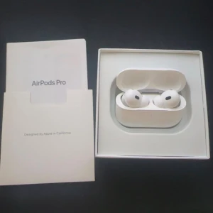 AirPods Pro 2 - Apple AirPods Pro i originalförpackning, komplett med laddningsetui, extra öronproppar i olika storlekar och laddningskabel. Allt ser mycket välvårdat ut, utan synliga skador eller slitage. Perfekt för dig som vill ha trådlösa hörlurar med aktiv brusreducering.