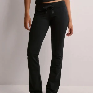 Lågmidjade mjukisbyxor - Snygga svarta mjukisbyxor med knytband i midjan. Byxorna har en bekväm passform och är perfekta för en avslappnad stil. De är tillverkade i ett mjukt material som ger en skön känsla hela dagen.