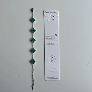 Green Alhambra bracelet - Snyggt armband i rostfritt stål med fem gröna fyrklöver-formade berlocker. Berlockerna har ett randigt mönster och är infattade i silverfärgad metall. Justerbar kedja med liten tag. Perfekt för dig som gillar unika detaljer! Mvh clover.se