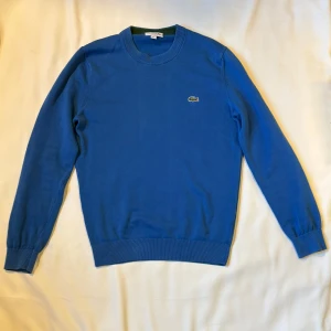 Blå tröja från Lacoste med logga - Snygg blå tröja från Lacoste med klassisk rund halsringning. Perfekt för dig som gillar lacoste storleken än s skriv för mer funderingar 