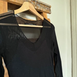 Svart meshklänning från AllSaints - Svart tight ribbstickad och supermjul långärmad klänning från AllSaints i storlek 34. Meshdetaljer upptill och på ärmarna, v-ringad. Något mindre tecken på användning men som knapp syns. ( nypris 2100 sek  ) 