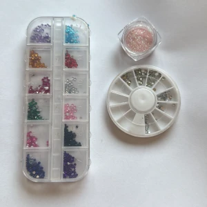 Ansiktsdiamanter & glitter till smink nagel stenar - Flera askar med ansiktsdiamanter i olika färger som lila, blå, röd, rosa, grön och silver samt en burk med rosa glitter. Perfekt för kreativa sminkningar och festivallooks. Kommer i praktiska förvaringsaskar i plast.