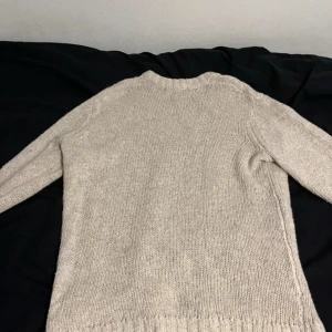 Beige stickad tröja från 157 - En enkel och snygg beige stickad tröja från 157. Tröjan har rund halsringning, långa ärmar och är ribbstickad vid hals, ärmslut och nederkant. Perfekt för lager-på-lager under kyliga dagar. Fråga gärna om mått eller att se den på. 