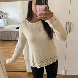 Beige stickad tröja med spetsdetaljer - Superfin beige stickad tröja med lång ärm och rund hals. Tröjan har snygga spetsdetaljer i ärmslut och längs nederkanten som ger en extra touch. Perfekt till jeans eller kjol för en chill och stilren look.