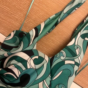 Grön mönstrad omlottklänning - Snygg festtopp som sitter jättebra! Passar bra till sommarn! Fin grön färg och bra styling med en kjol shorts eller långabyxor