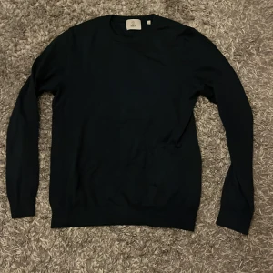 Blå långärmad tröja från Bläck - En stilren svart långärmad tröja från Bläck i storlek S. Tröjan har rund halsringning och är tillverkad i ett mjukt material som passar perfekt till lager-på-lager. Enkel och clean design som funkar till många olika looks.