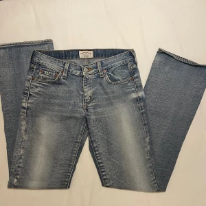 Crocker Originals - Crocker jeans med låg midja, vidare benslut, slitna partier. Midja: 37cm. Innerben: 77 cm. Benslut: 20 cm