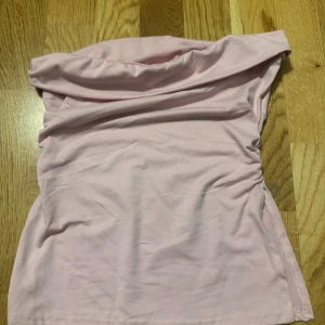 Ljusrosa tubtopp från Shein XS - Säljer en ljusrosa tubtopp från Shein i storlek XS. Toppen är axelbandslös och har en enkel, slät design med lätt rynkning på sidorna. Mjuk och stretchig bomullskänsla som sitter tight och snyggt. Perfekt för dig som gillar minimalistisk stil. Andra bilden är den riktiga färgen.
