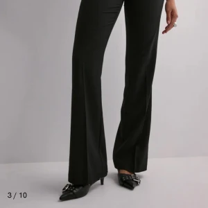 Svarta kostymbyxor - Snygga kostymbyxor från Nelly, svarta lågmidjad. Inte använda många gånger, säljer då de inte kommer till användning. Vid intresse kan fler bilder skickas!.