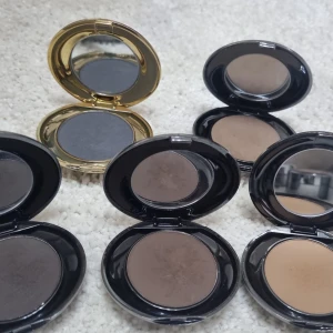 Set med ögonskuggor i naturtoner - Flera ögonskuggor i olika bruna och grå nyanser, perfekta för att skapa både naturliga och mer markerade ögonlooker. Kommer i svarta och en guldig rund dosa, alla med spegel i locket. Pudrig formula som är lätt att blenda. 50kr/st
