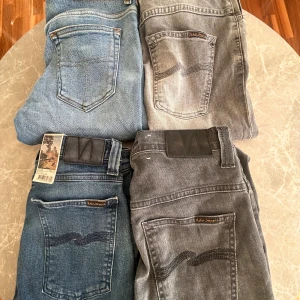 Nudie Jeans i blått och grått och tiger of Sweden  - Fyra par Nudie Jeans i olika tvättar – två blå och två grå. Klassisk femficksmodell med Nudie-logga på bakfickan och svarta läderpatches i midjan. Snygga kontrastsömmar och slitna detaljer för en cool look. Perfekta jeans för dig som gillar streetstyle.
