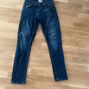Morris Steve Satin Jeans blå 30/32 - Snygga blå jeans från Morris, modell Steve Satin Jeans. Klassisk femficksdesign med kontrastsömmar och läderpatch bak. Jeansen har rak passform och är tillverkade i mjukt denimtyg som sitter skönt hela dagen.