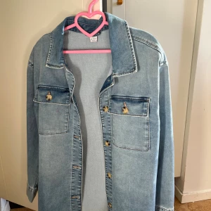 Ljusblå jeansjacka med fickor - Snygg ljusblå jeansjacka i klassisk modell med två bröstfickor och knappar framtill. Jackan har långa ärmar och en rak passform. Perfekt för dig som gillar en avslappnad och tidlös stil, har använts knappt (bara ett par gånger) och är från Lindex. Ställ frågor om ni är intresserade ❤️