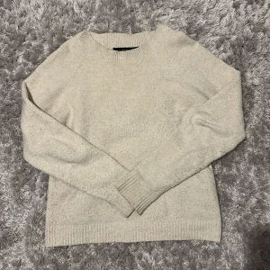 Beige stickad tröja från Vero Moda - Mysig beige stickad tröja från Vero Moda i storlek M. Tröjan har rund hals, ribbade muddar och långärmad design. Perfekt för att hålla dig varm under kyliga dagar och passar till jeans eller kjol för en chill look.