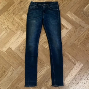 Tiger of Sweden skinny jeans blå - Snygga blå jeans från Tiger of Sweden med smal passform och klassisk femficksdesign. Jeansen har en mörk tvätt med lätt slitning och kontrastsömmar. Perfekta för dig som gillar en stilren och modern look.