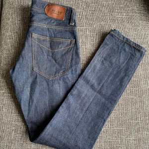 Mörkblå jeans från NN07 28/32 - Säljer ett par mörkblå jeans i klassisk rak modell. Jeansen har kontrastsömmar, fem fickor och är tillverkade i slitstarkt bomullsjeans. Perfekt passform och snyggt läderpatch bak i midjan.