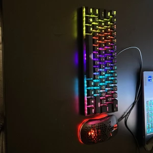 Dacota Gamingtangentbord & Ultralätt Dacota Gamingmus - Snyggt mekaniskt tangentbord med RGB-belysning och ultralätt gamingmus med röd LED. Perfekt för gaming, responsiva tangenter och bekväm design. Båda i mycket gott skick, inga synliga defekter eller slitage.