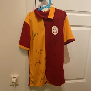 Galatasaray  Signerad matchtröja XS - Unik Galatasaray fotbollströja i XS med Icardi 9 på ryggen och flera autografer på framsidan. Signerad av: ICARDI, MUSLERA, ZAHA, TETE, SACABOEY, TOREIRA, KEREM, NELSON, OLIVIERA. Signerad direkt från spelarna. Xs 