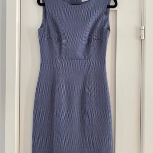 Blåvit rutig klänning från MAX&Co - Snygg ärmlös klänning från MAX&Co i blått och vitt med rutigt mönster. Modellen är figurnära med rund halsringning och dragkedja i sidan. Perfekt för dig som gillar stilrena och klassiska plagg med en modern twist. Mått Över bröstet: ca 44 cm Över höften: ca 46 cm Längd från axeln och ner: ca 92 cm  69% polyester, 29% viskos och 2% elastan  Kommer från ett djur och rökfritt hem.