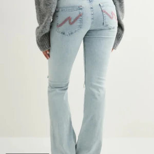 Ljusblå lowaist bootcut jeans med broderi - Säljer ett par ljusblå bootcut jeans med slitna knän och rosa broderad detalj på bakfickorna. Uppsydda hos skräddare så de passar mig som är 160. 