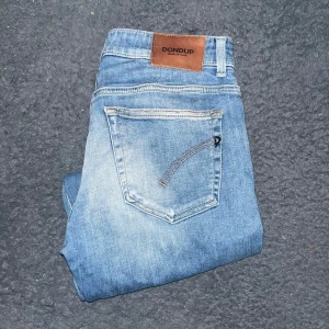 Dondup jeans - Snygga ljusblå jeans från Dondup i modellen Rose Cropped Slim Fit. Jeansen har slitna detaljer och en klassisk femficksdesign med bruna läderpatch bak. OBS vet ej om det är dam heller herr. Ifall det inte finns någon bild i annonsen där jag bär plaggen jag säljer så är det för att jag ej kan ha storleken heller passformen, så kolla måtten för storlek och googla på modellnamnet för passform 😉(8)