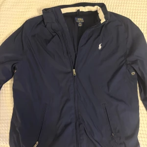 Ralph Lauren vindjacka - Snygg marinblå vindjacka från Polo Ralph Lauren med vit logga på bröstet. Perfekt till hösten. Skick 7/10, nypris 2500 ungefär. Skriv vid minsta lilla fundering. Snabb affär = bra pris