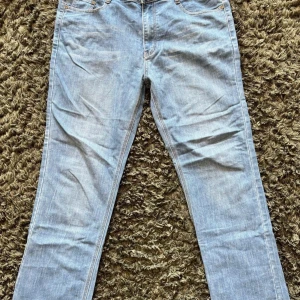 Levis 501 W32 L33 - Ljusblå klassiska Levi's 501 jeans i rak modell med fem fickor och snygga kontrastsömmar. Jeansen har normal passform och är tillverkade i slitstarkt bomullsdenim. Perfekt för dig som gillar tidlös stil och vill ha ett par jeans som funkar till allt.