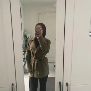 Beige trenchcoat med bälte - Snygg beige trenchcoat med bred krage och knytbälte i midjan. Jackan har en passform och långa ärmar. Perfekt för dig som gillar stilrena och tidlösa plagg. Materialet känns mjukt och har en lätt struktur.