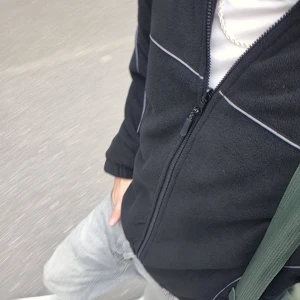 Svart fleecejacka - Svart fleecejacka från Urban Outfitters med vita kontrastsömmar och dragkedja framtill. Jackan har hög krage, elastiska muddar och en sportig vibe. Perfekt för kyliga dagar och enkel att matcha med det mesta. Har kvar kvitto