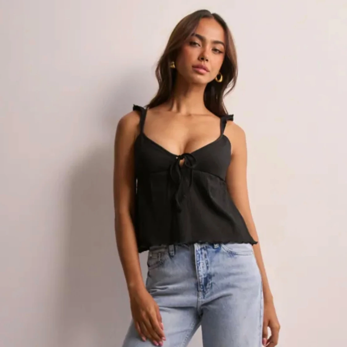 Nelly Svart linnetopp med knyt och volang