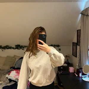 Grå sweatshirt från Gina Tricot - En enkel och stilren ljusgrå sweatshirt från Gina Tricot, basically basics-kollektionen. Tröjan har rund hals, ribbade muddar och långärmad passform. Perfekt för chill dagar och enkel att matcha med jeans eller leggings.