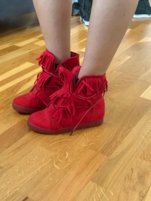Röda mockaboots med fransar Isabel marant liknande  - Liknande Isabel marant ‼️Snygga röda boots i mocka med coola fransdetaljer runt hela skaftet. Skorna har snörning framtill och en platt sula som ger en avslappnad vibe. Perfekta för dig som vill sticka ut med din stil och gillar färgstarka accessoarer.
