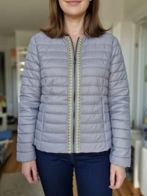 Ny jackan  - Snygg grå jacka med guldfärgad dekorativ dragkedja. Jackan är kort och har en avslappnad passform.