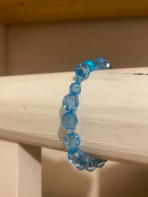 Handgjort armband med olika blåa nyanser 🐳 - Snyggt armband med facetterade blå pärlor i plast. Pärlorna är genomskinliga och ger ett glittrande intryck. Armbandet är elastiskt och passar de flesta handleder. Perfekt accessoar för att addera lite färg till din stil. 🌊