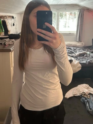 Vit långärmad topp i bomull - En basic vit långärmad topp med rund halsringning. Sitter tight och är gjord i mjukt bomullsmaterial, perfekt att styla med jeans eller kjol. Enkel och stilren design utan synliga detaljer.