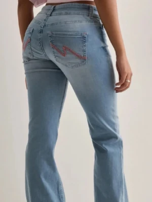 Nelly jeans  - Säljer ett par trendiga ljusblå bootcut jeans med snygga rosa sicksacksömmar på bakfickorna från Nelly. 