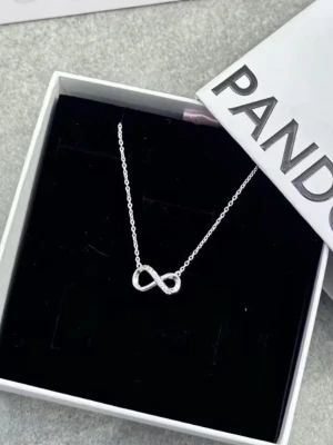 Pandora halsband med evighetssymbol - Säljer ett stilrent silverfärgat halsband från Pandora med en gnistrande evighetssymbol dekorerad med små stenar. Kedjan är tunn och smidig, perfekt för att lyfta vilken outfit som helst. Kommer i originalask.