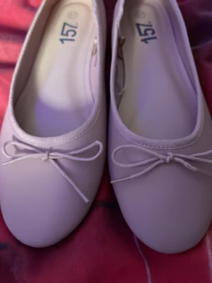 Ljusa ballerinaskor med rosett - Säljer ett par ljusa ballerinaskor med rund tå och söt rosettdetalj framtill. Skorna har en enkel och klassisk design med slät yta och mjukt material. Perfekta för dig som gillar stilrena och feminina skor.