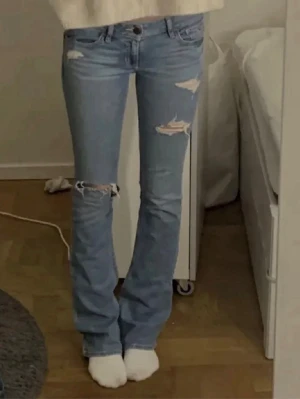 Snygga lowwaist bootcut jeans - Säljer ett par snygga ljusblå bootcut jeans från Hollister. Storlek W27 L33. De är lagande av en skräddare, på grund av tidigare hål. (Se sista bilden) men ingenting som märks av. Skriv för fler bilder eller vid funderingar❣️