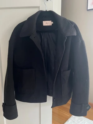 Svart kappa från Nelly - Säljer denna kappa som jag inte använder så mycket längre. Den är stilren och har fina knappar som detaljer. Varm och skön och passar till allt🤍